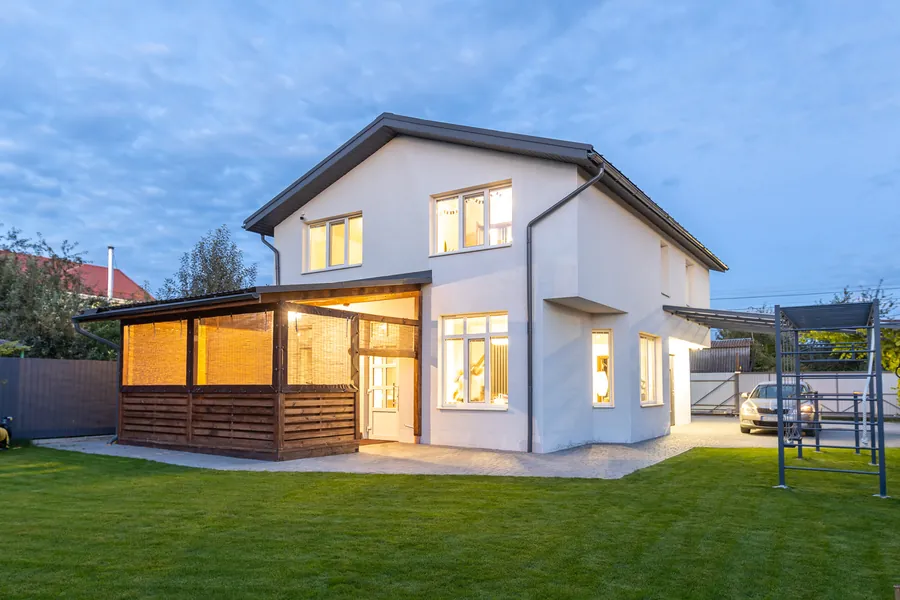 Fertiggestelltes Haus mit Terrasse und angelegtem Garten, am Abend